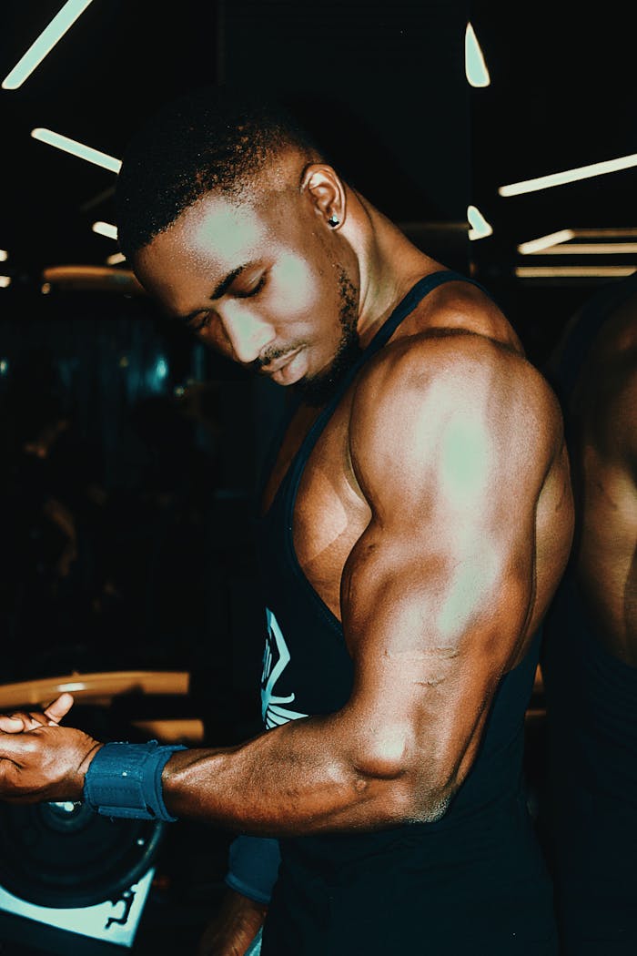 about-img Black man demonstrating muscular physique in gym, highlighting strength and fitness.