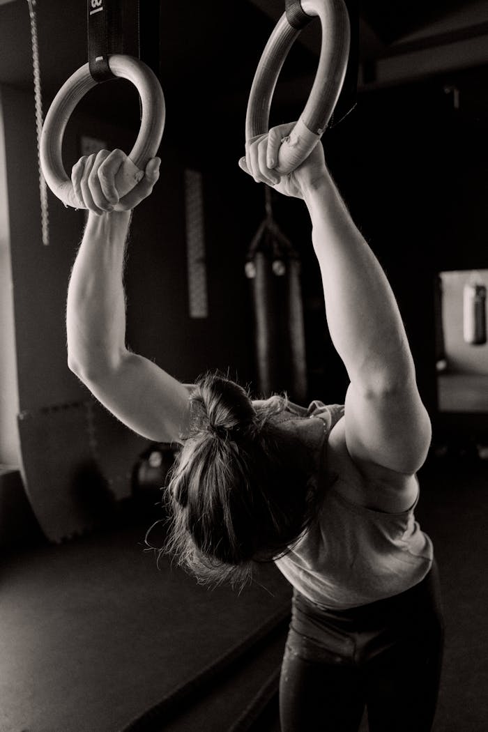services-img Man performing strength training with gymnastic rings in gym setting.
