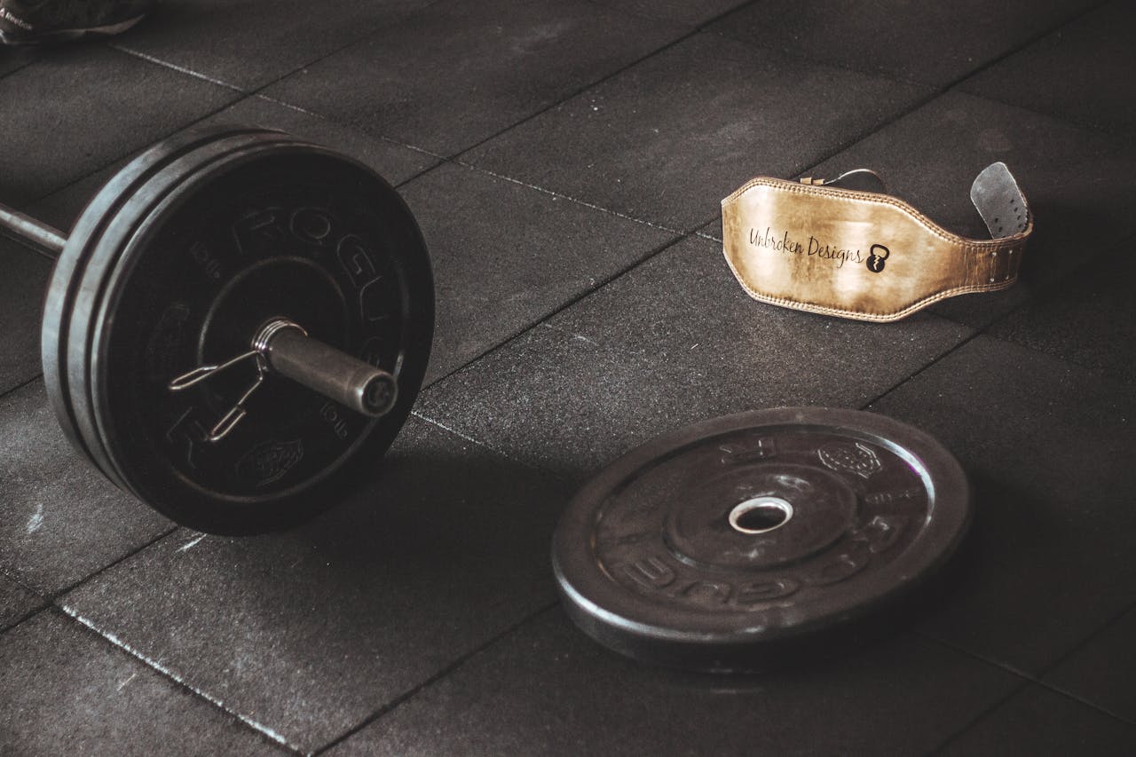 services-04 A heavy barbell and weightlifting belt on a gym floor, emphasizing strength and fitness.